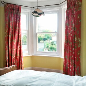Master bedroom curtains in warm coral textile by Thibaut, triple pleats and pole by Bradley Collection